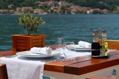 Karadağ 'daki Adriyatik Denizi Kotor Körfezi kıyısında deniz manzaralı bir restoranda masa