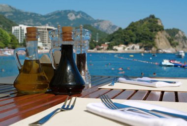 Karadağ 'da deniz manzaralı restoranda soya sosu, zeytinyağı, biber ve tuz masada.
