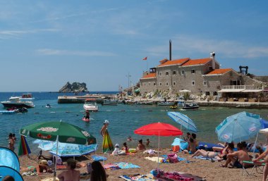 Petrovac, Karadağ, 1 Temmuz 2019: Karadağ 'ın Adriyatik Denizi' ndeki Petrovac kentindeki plajda yaşayan insanlar eski kente bakıyorlar