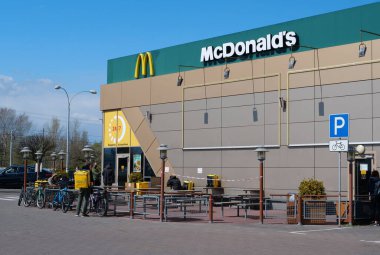 KYIV, UKRAINE, 20 NİSAN 2020: bisikletli kuryeler McDonalds fast food restoranının yakınlarında siparişleri bekliyor. Covid-19 salgını sırasında restoran sadece arabalar için çalışır.