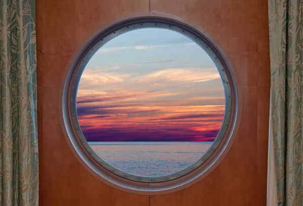 Oceaan en 's avonds hemel zonsondergang gezien door de patrijspoort van een schip — Stockfoto