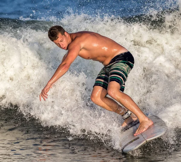 Junger Mann surft auf einer Welle — Stockfoto