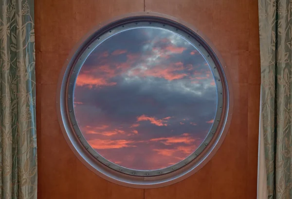 Sunset seen through the porthole of a ship Stock Picture