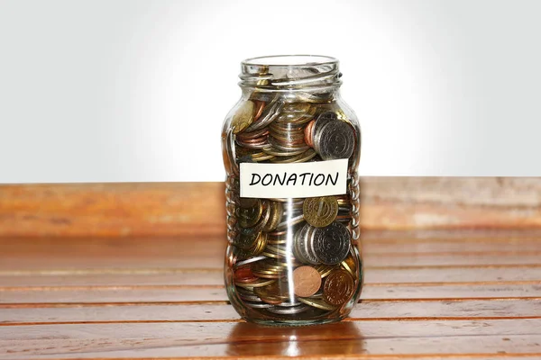 Een glazen pot vol munten aan vertegenwoordigt donatie c — Stockfoto