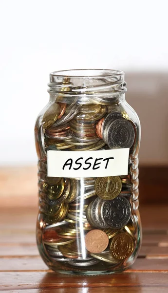 Un frasco lleno de monedas - con etiqueta de activos — Foto de Stock