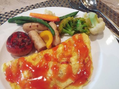 Sosisli omlet kahvaltısı ve ketçaplı domates.