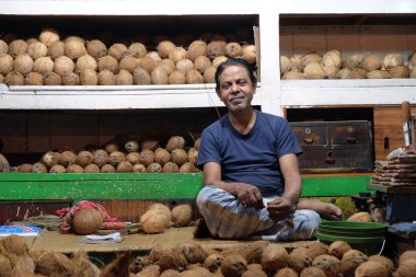 Hint satıcı tenli kahverengi Hindistan cevizleri Kolkata yeni pazarda büyük bir yığın arkasına 11 Şubat 2016 üzerinde oturur.