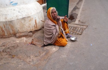 Beggar waits for alms on a street on the ghat along the sacred Sarovar lake in Pushkar, India on February 18, 2016. clipart