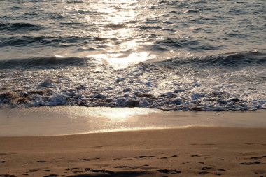 Candolim Sahili, Kuzey Goa, Hindistan 'daki kumların üzerinde dalgalar dönüyor.