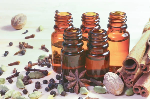 Essential oils in glass bottles and spices on wooden background with copyspace