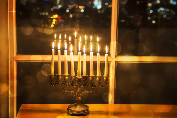 Menorah (candlestick with 8 candles) by the window with the night city view