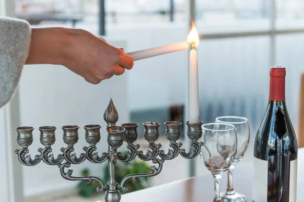 Litting up Menorah (candlestick with 8 candles) by the window — Stock Photo, Image