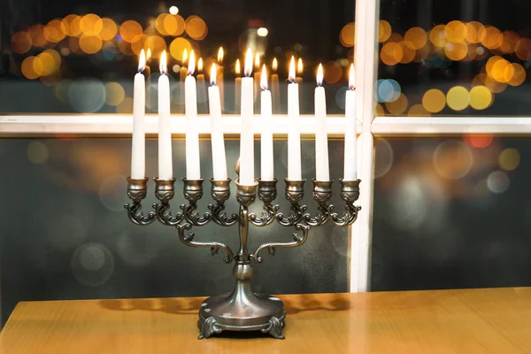 Jewish holiday Hanukkah with menorah by the window