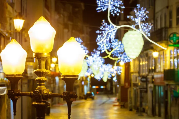 Θέα σε έναν αρχαίο ευρωπαϊκό φωτισμένο δρόμο τη νύχτα των Χριστουγέννων Εικόνα Αρχείου