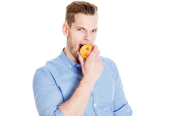 Joven hombre guapo está mordiendo una manzana aislada en blanco — Foto de Stock