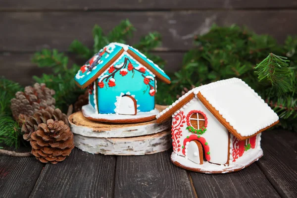 Zwei weihnachtliche Lebkuchenhäuser auf Holztisch, Gimpel und Vogelbeerendekor. — Stockfoto