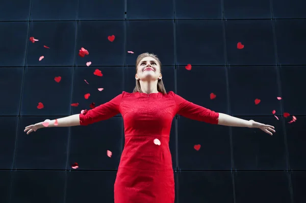 Walentynki w koncepcji, Kobieta w czerwonej sukience dmuchanie na serce papieru. — Zdjęcie stockowe