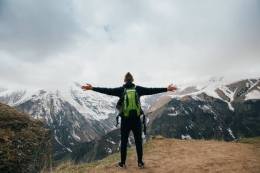 Sırt çantası konumu bir dağın tepesinde kaldırdı elleriyle olan genç adam