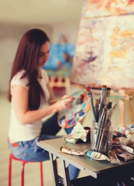 Kadın sanatçı Studio resim üzerinde çalışıyor. Arka plan resmi, ön plan üzerinde seçici odak