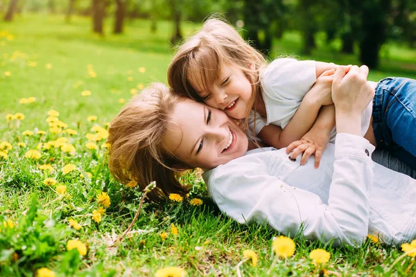 Objímání happy matka a dcera na procházku v parku na zeleném trávníku — Stock fotografie