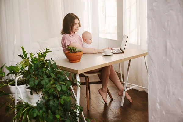 Μαμά και μωρό. μια νεαρή μητέρα που εργάζεται με φορητό υπολογιστή στο σπίτι. — Φωτογραφία Αρχείου