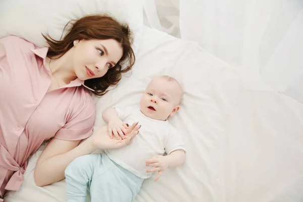 Portrait d'une jeune belle maman caucasienne et bébé sur le lit. Vue de dessus. Espace de copie — Photo
