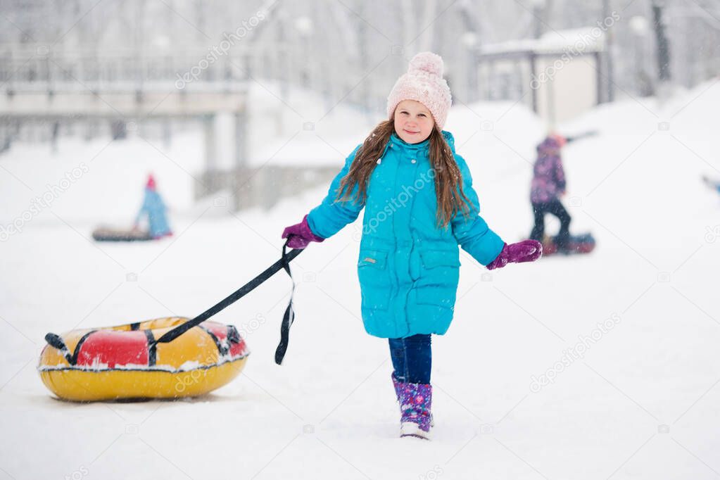 Girl having fun on snow tube.Girl is riding a tubing. Winter holidays, holiday for children in winter. Winter city park.