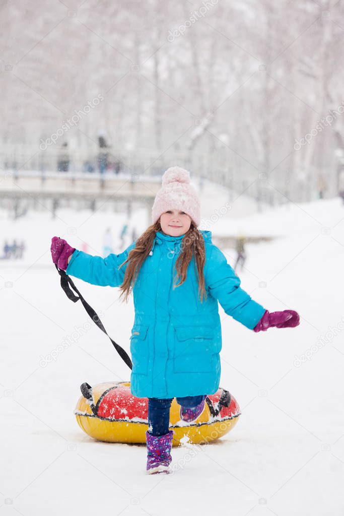 Girl having fun on snow tube.Girl is riding a tubing. Winter holidays, holiday for children in winter. Winter city park.
