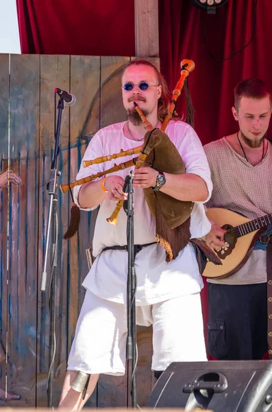 Portret van een mannelijke muzikant in traditionele middeleeuwse kleren spelen — Stockfoto