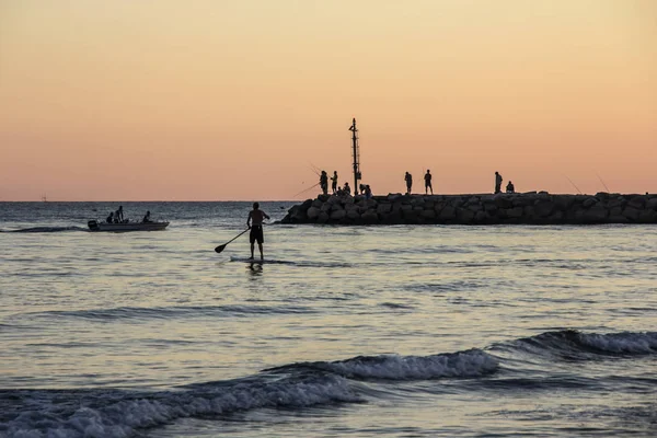 Puesta de sol en el mar Tirreno, vista del rompeolas, surfista SUP, puerto y costa de Terracina, Lazio, Italia —  Fotos de Stock
