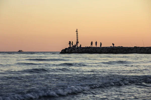 Puesta de sol en el mar Tirreno, vista de rompeolas, siluetas de pescadores, puerto y costa de Terracina, Lazio, Italia —  Fotos de Stock