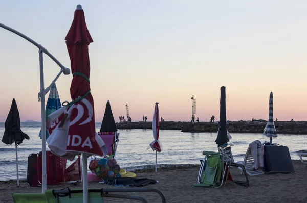Puesta de sol en el mar Tirreno, vista del rompeolas, sombrillas de playa, puerto y costa de Terracina, Lazio, Italia —  Fotos de Stock