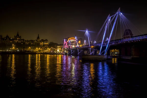 Hungerford Bridge e Golden Jubilee Bridges e Whitehall Gardens di notte con luci riflesse nell'acqua del Tamigi, Londra — Foto Stock