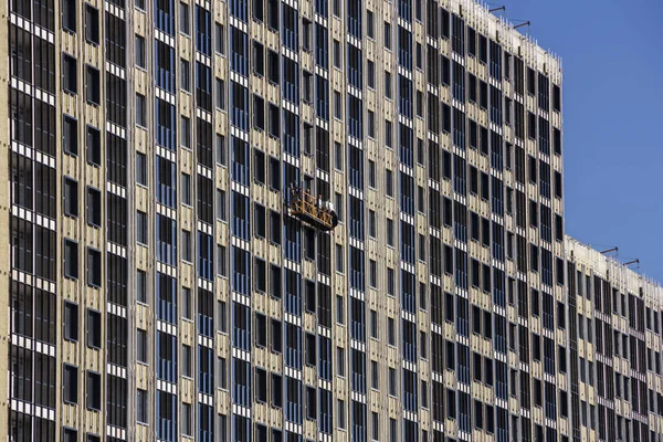 Construção de decoração da fachada por construtores em um berço de construção de novos edifícios residenciais e guindastes de torre — Fotografia de Stock