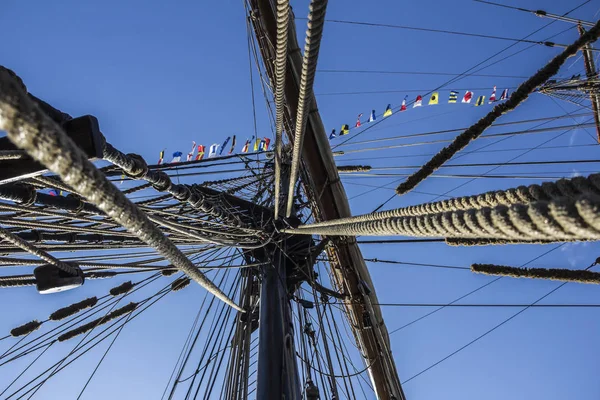 Nautischer Teil einer Jacht oder eines großen alten Segelschiffs mit Schnüren, Takelage, Segel, Masten, Knoten, Signalflaggen vor blauem Himmel — Stockfoto