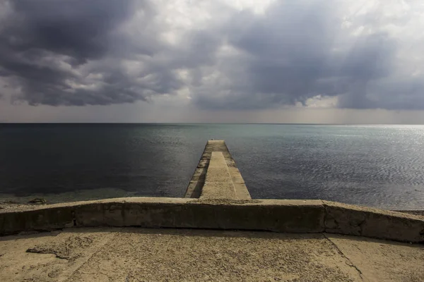 Una vista al rompeolas de hormigón, un muelle y un horizonte marítimo desde el terraplén —  Fotos de Stock
