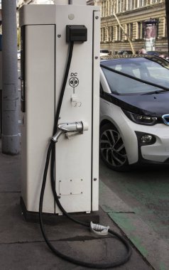 Elektrikli araba şarjı için güç kaynağı. Elektrikli araba şarj istasyonu. Şarj edilen bir elektrikli arabaya takılan güç kaynağını kapatın.. 