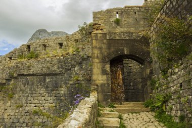 Karadağ, Kotor, 09 Ekim 2019. Eski kasabanın eski Kotor duvarlarında ve Kotor Kalesi 'nin (St John Kalesi) antik duvarlarında ve Kotor kasabasının yamacındaki dağlarda bulunan Kurtuluş Anıtı Kilisesi' nin (Bas-Relivation) manzarası. Unesco.