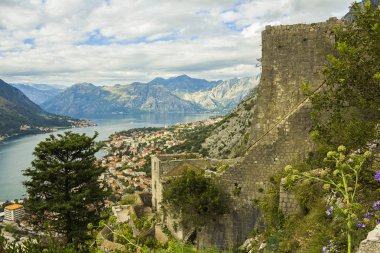 Karadağ, Kotor, 09 Ekim 2019. Eski kasabanın eski Kotor duvarlarında ve Kotor Kalesi 'nin (St John Kalesi) antik duvarlarında ve Kotor kasabasının yamacındaki dağlarda bulunan Kurtuluş Anıtı Kilisesi' nin (Bas-Relivation) manzarası. Unesco.