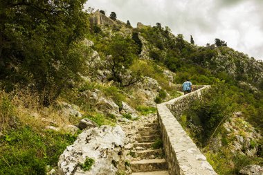 Karadağ, Kotor, 09 Ekim 2019. Eski kasabanın eski Kotor duvarlarında ve Kotor Kalesi 'nin (St John Kalesi) antik duvarlarında ve Kotor kasabasının yamacındaki dağlarda bulunan Kurtuluş Anıtı Kilisesi' nin (Bas-Relivation) manzarası. Unesco.