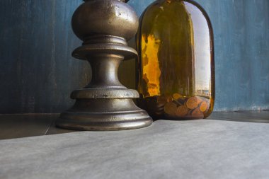 Üzerinde bozuk paralar olan büyük kahverengi cam kavanoz ve üzerinde beyaz mum bulunan devasa şamdan mavi eski püskü duvar arka planı, tasarruf, ticaret, tasarruf veya elektrik ekonomisi kavramı