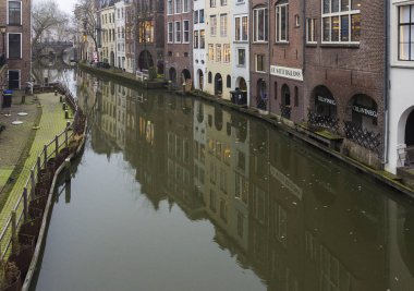  Utrecht, Hollanda, 21 Ocak 2020. Utrecht 'in merkezindeki kanal boyunca çift yay taş köprü. Misty Evening, kanalın gece manzarası, eski Hollandalı evler, kanal boyunca bisikletler.