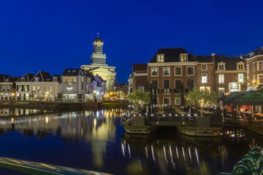 Leiden, Hollanda, Hollanda, 16 Ocak 2020. Her yere parkedilmiş bisikletlerin gece görüşü, köprüler, sokaklar, kanallar, kafeler, eski kentte mavna, denizde kayıklar, bisikletçiler, şehirdeki insanlar.