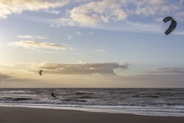 Günbatımında rüzgârlı bir kış gününde kuzey sahili manzarası, millet, uçurtma. Noordwijk, Hollanda