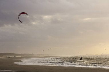Günbatımında rüzgârlı bir kış gününde kuzey sahili manzarası, millet, uçurtma. Noordwijk, Hollanda