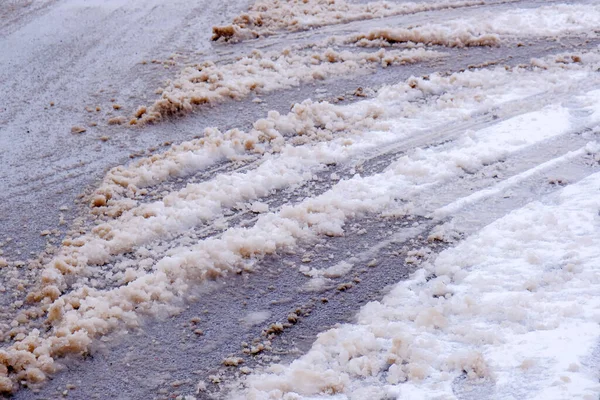 Асфальтированная дорога покрыта тающим снегом — стоковое фото