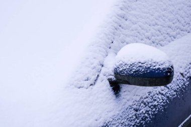 Açık otoparkta kar kaplı bir araba.