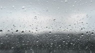 Yağmur damlaları ve şehir manzaralı video klip penceresi. Yağmurlu, yağmurlu, bulutlu bir gün. Video arkaplanı bulanık.