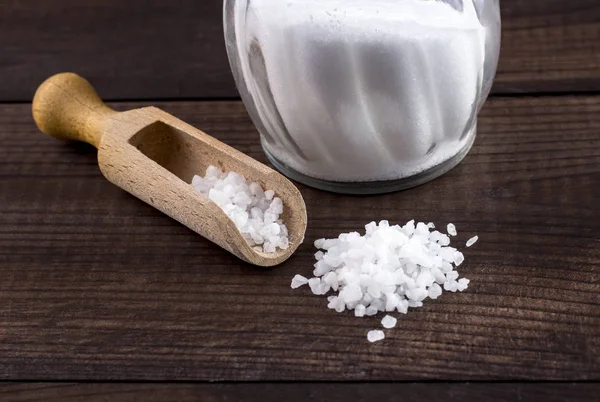Соль с деревянной ложкой и стеклянной солонкой — стоковое фото