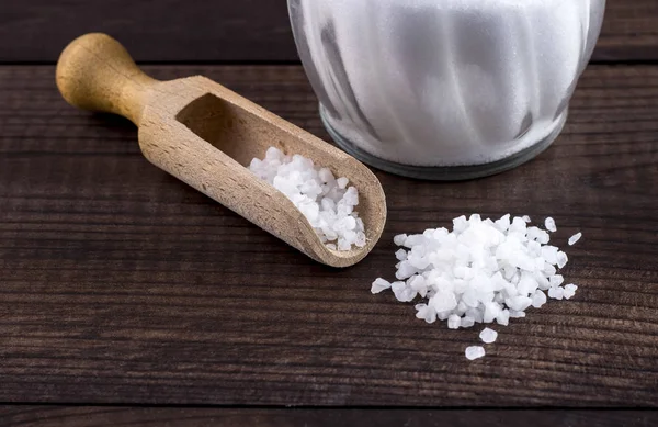 Соль с деревянной ложкой и стеклянной солонкой — стоковое фото